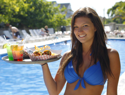 server with various food items and drinks outside by the pool