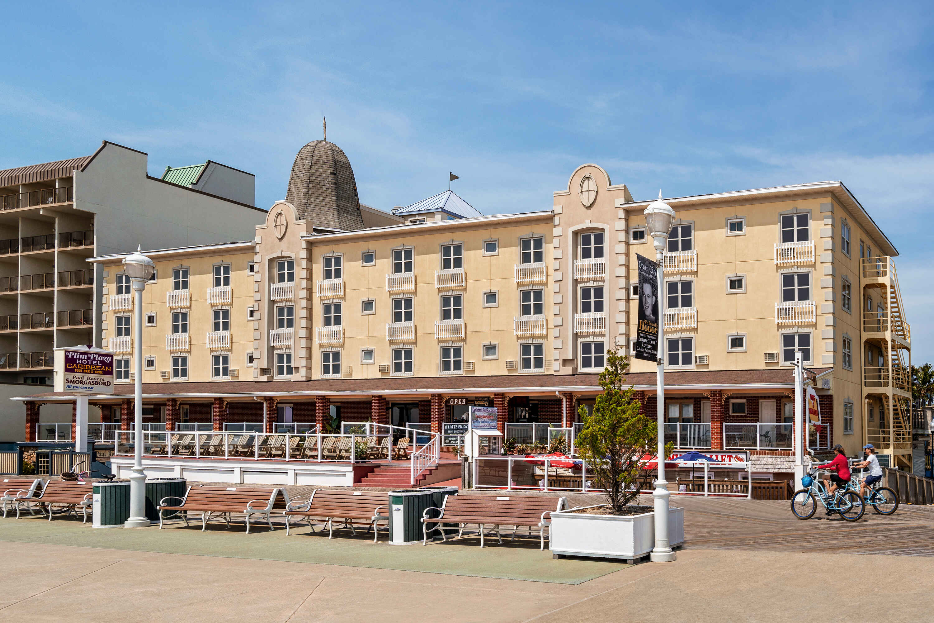 A large, multi-story hotel with balconies and a boardwalk in front of it.