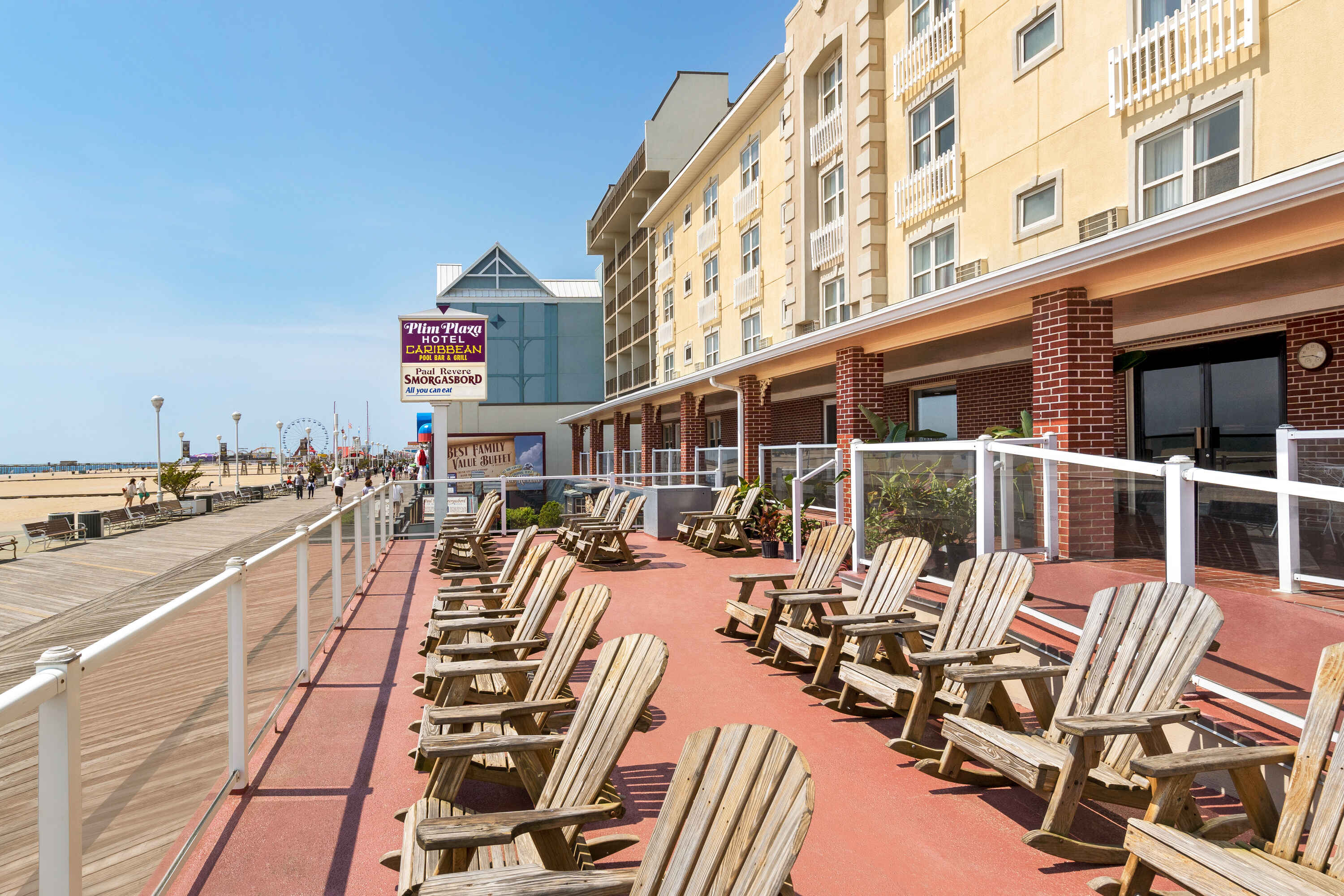 A hotel exterior with a balcony overlooking a boardwalk and beach