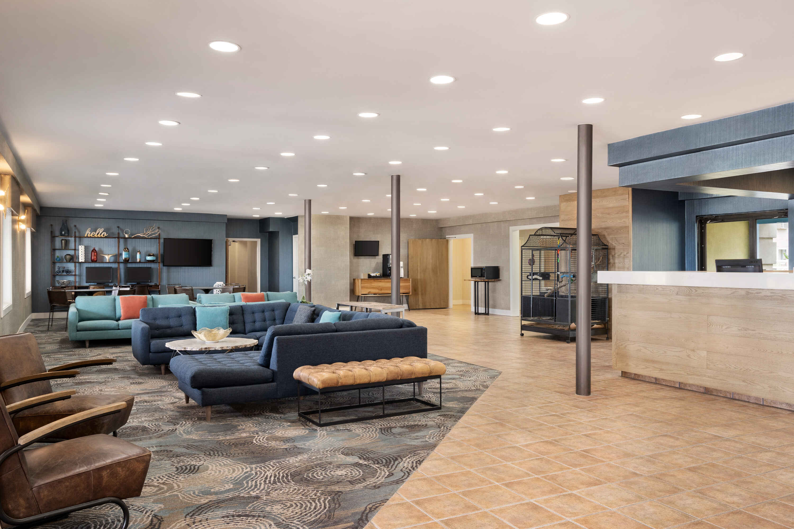 A hotel lobby with a reception desk, seating area, and TV.