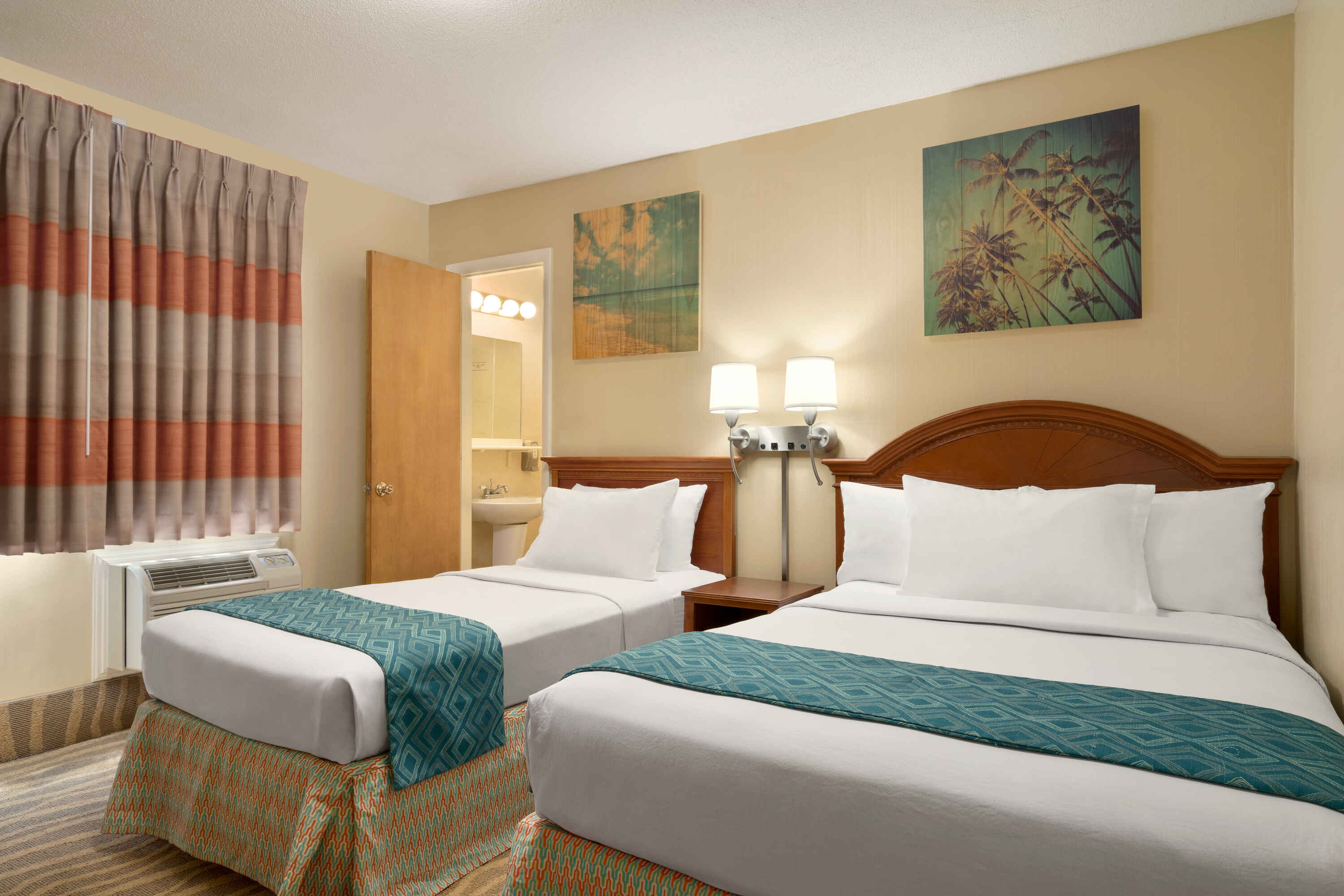 A hotel room with two beds, a nightstand, and artwork on the walls.