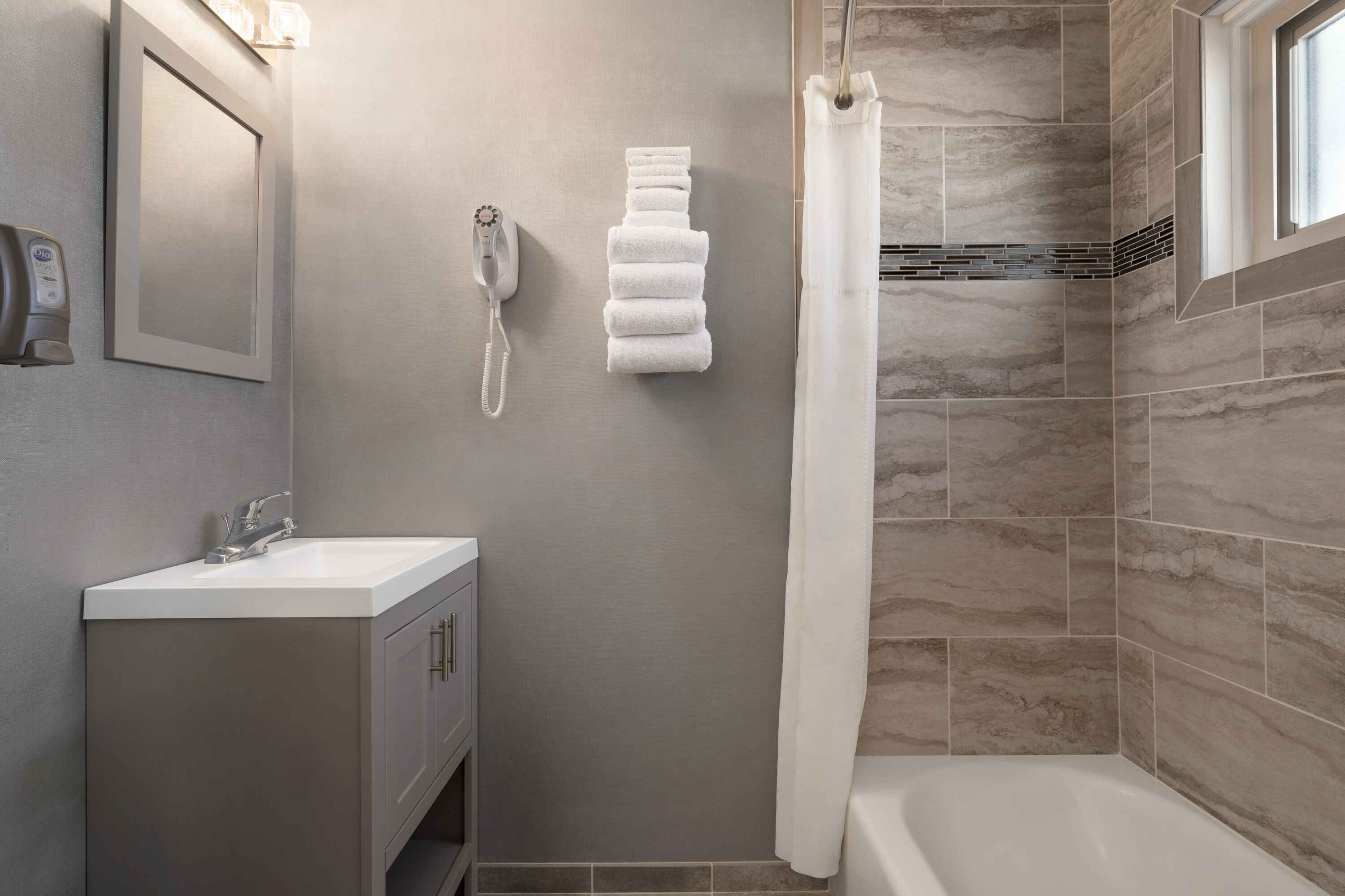 A clean bathroom with a sink, mirror, towels, shower, and bathtub.