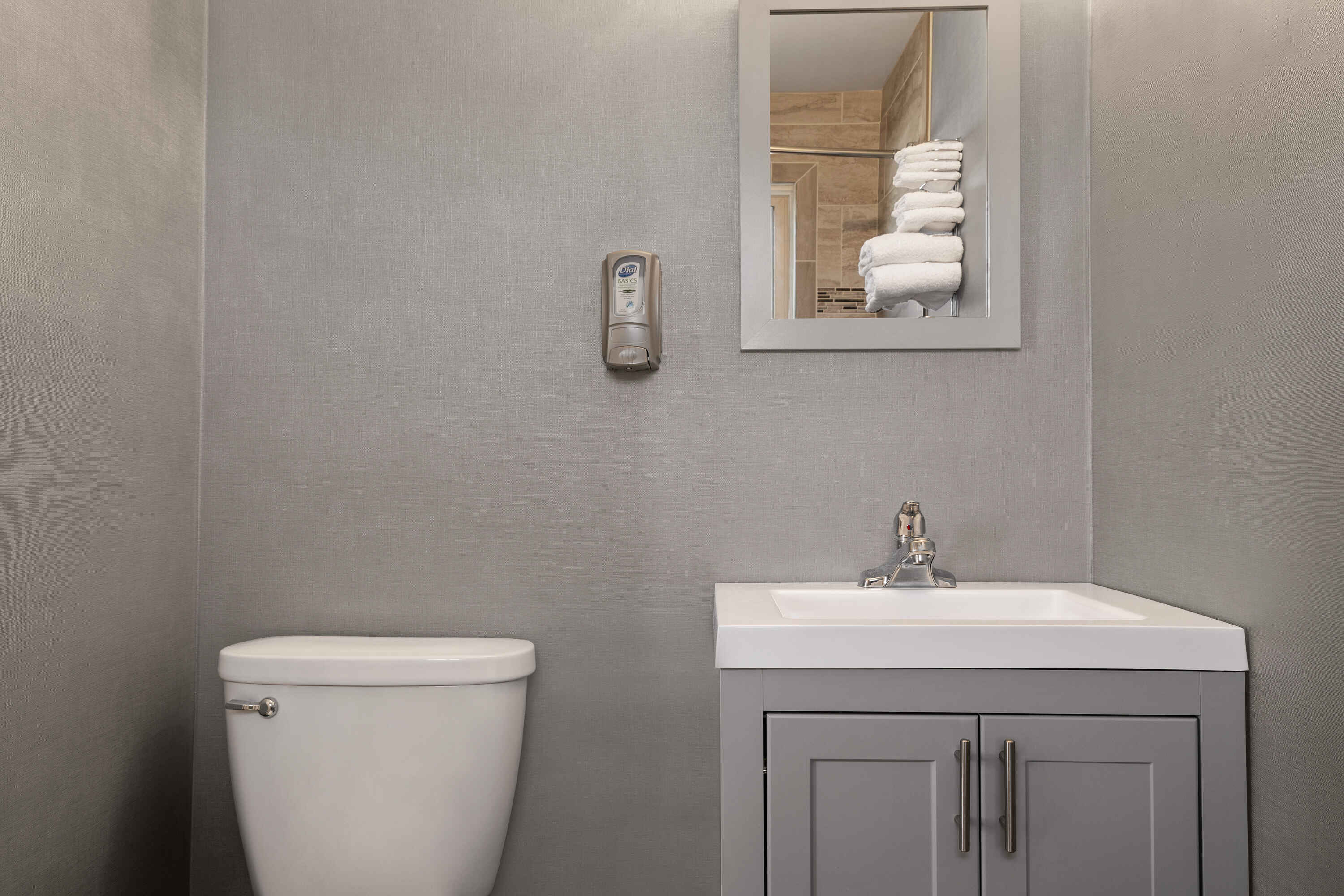 A bathroom with a toilet, sink, and mirror with towels.