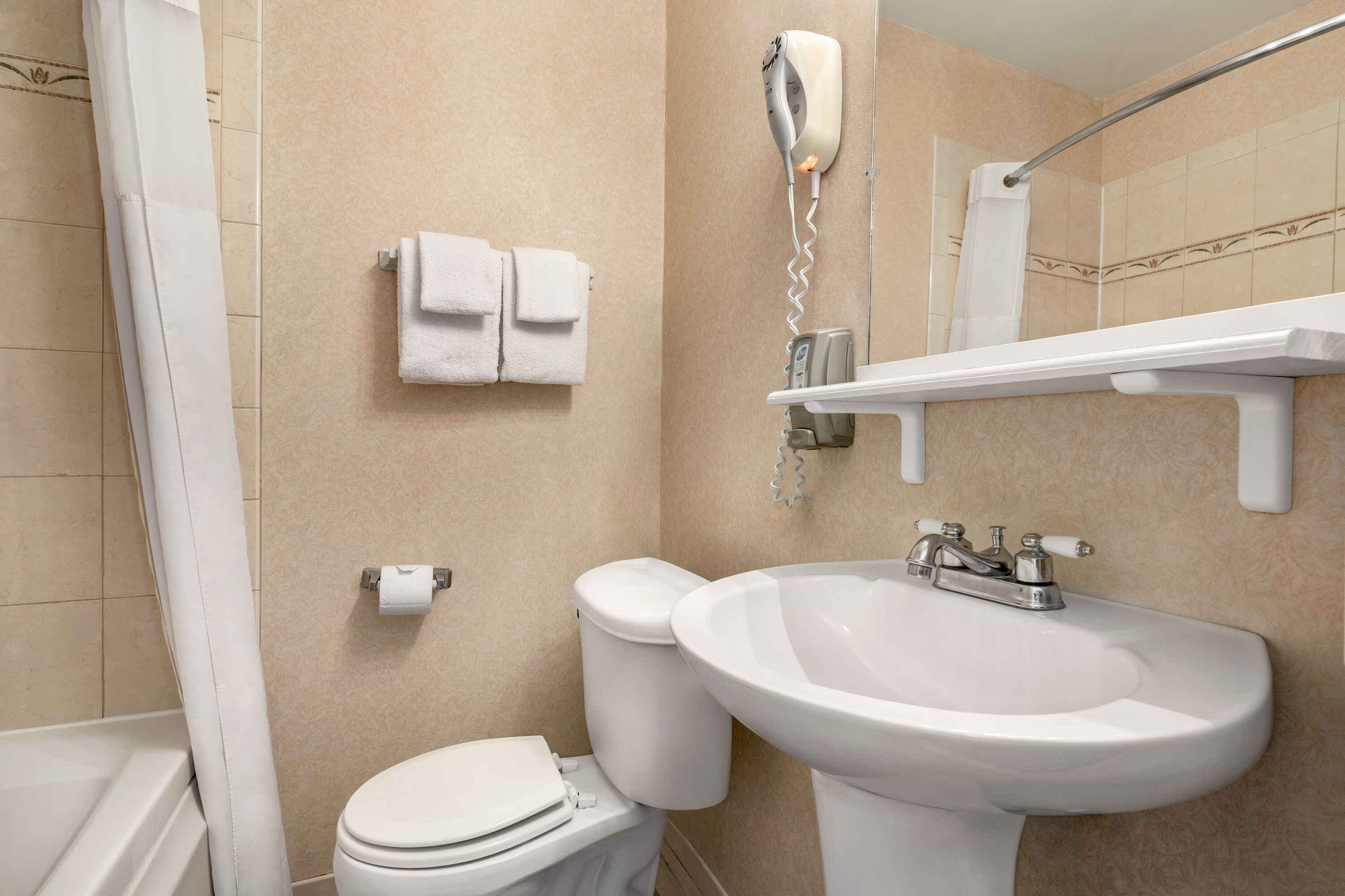 A bathroom with a toilet, sink, shower, and towels