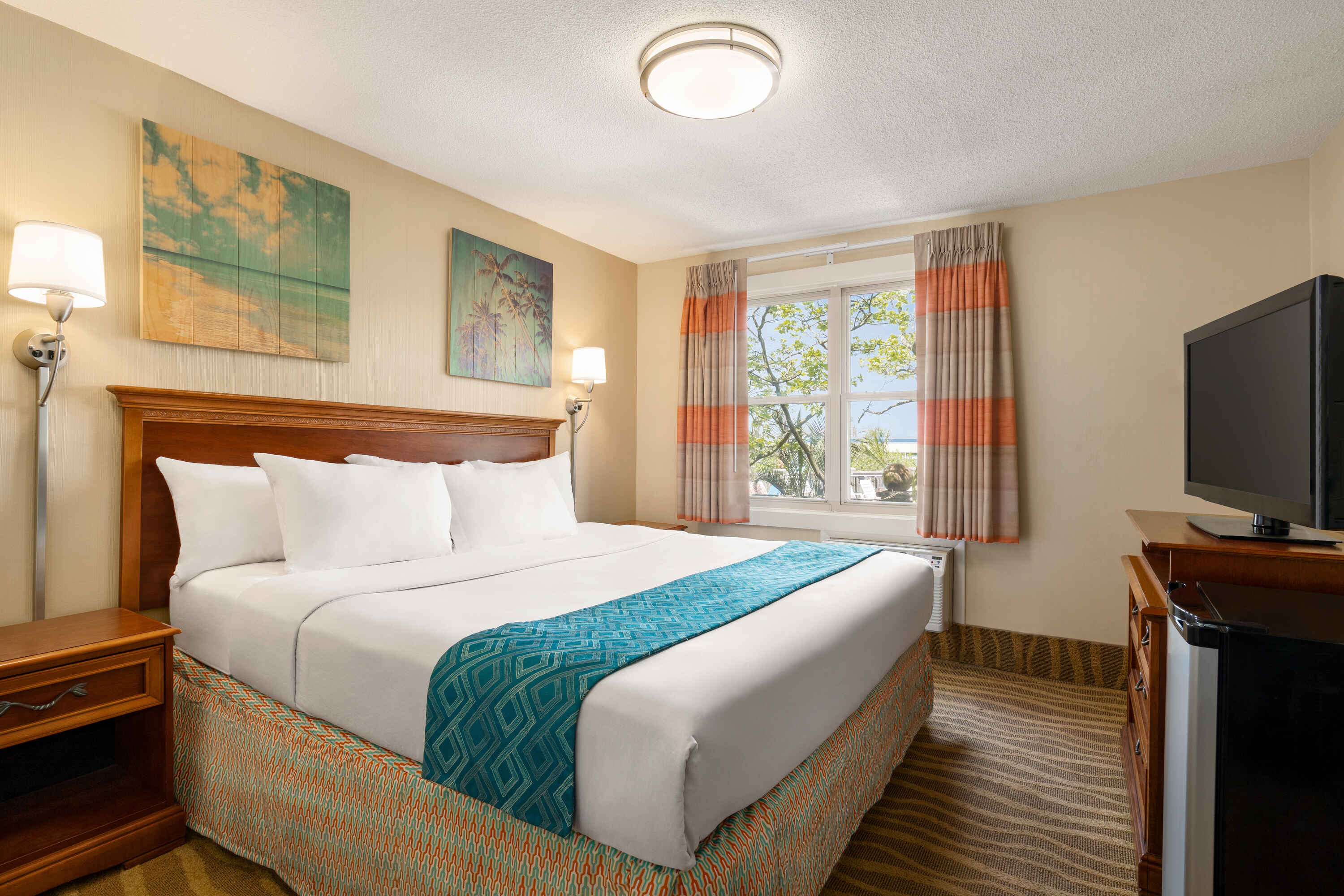 A hotel room with a large bed, TV, and window