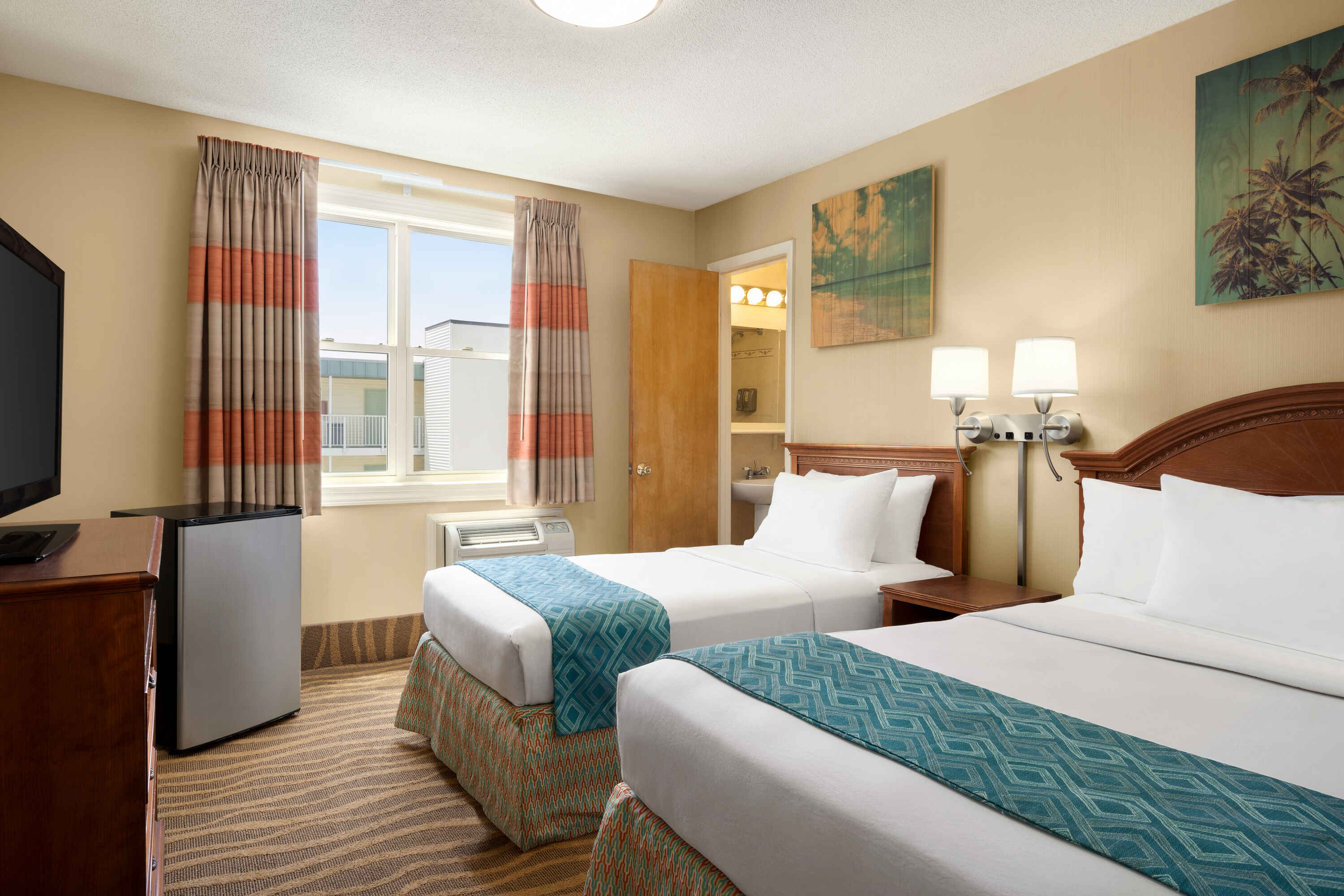 A hotel room with two beds, a window, and a TV.