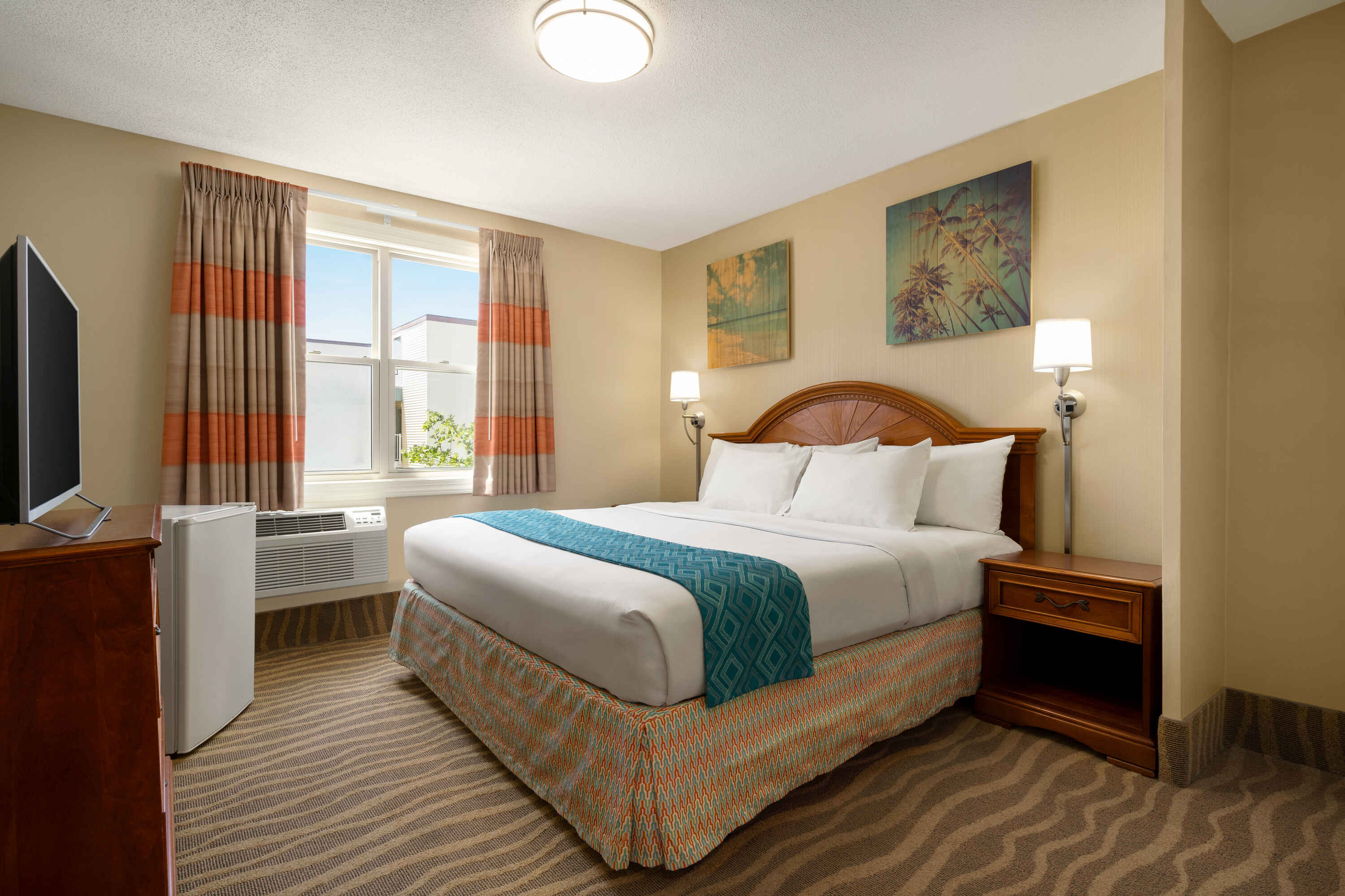 A hotel room with a bed, nightstand, TV, and window.