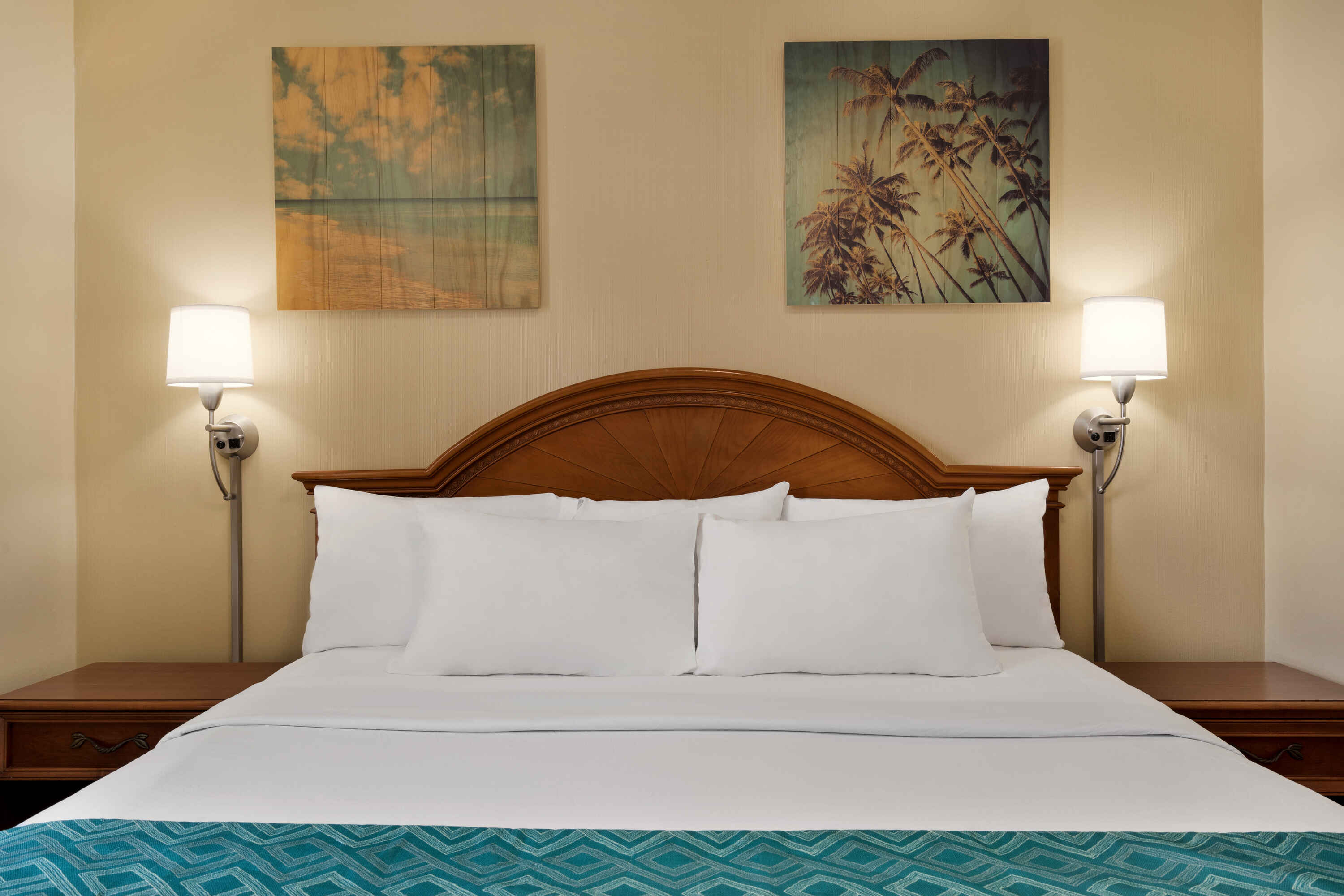 A neatly made bed with a wooden headboard, two nightstands, and two lamps in a hotel room.